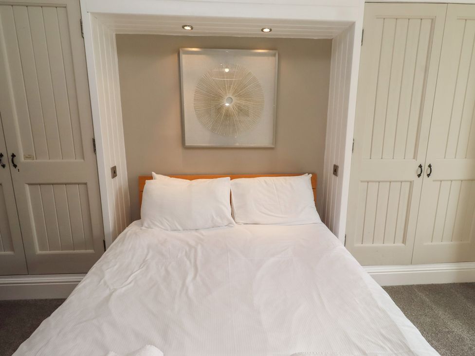 A bed with pillows and artwork in a bedroom at Rose House Alnmouth