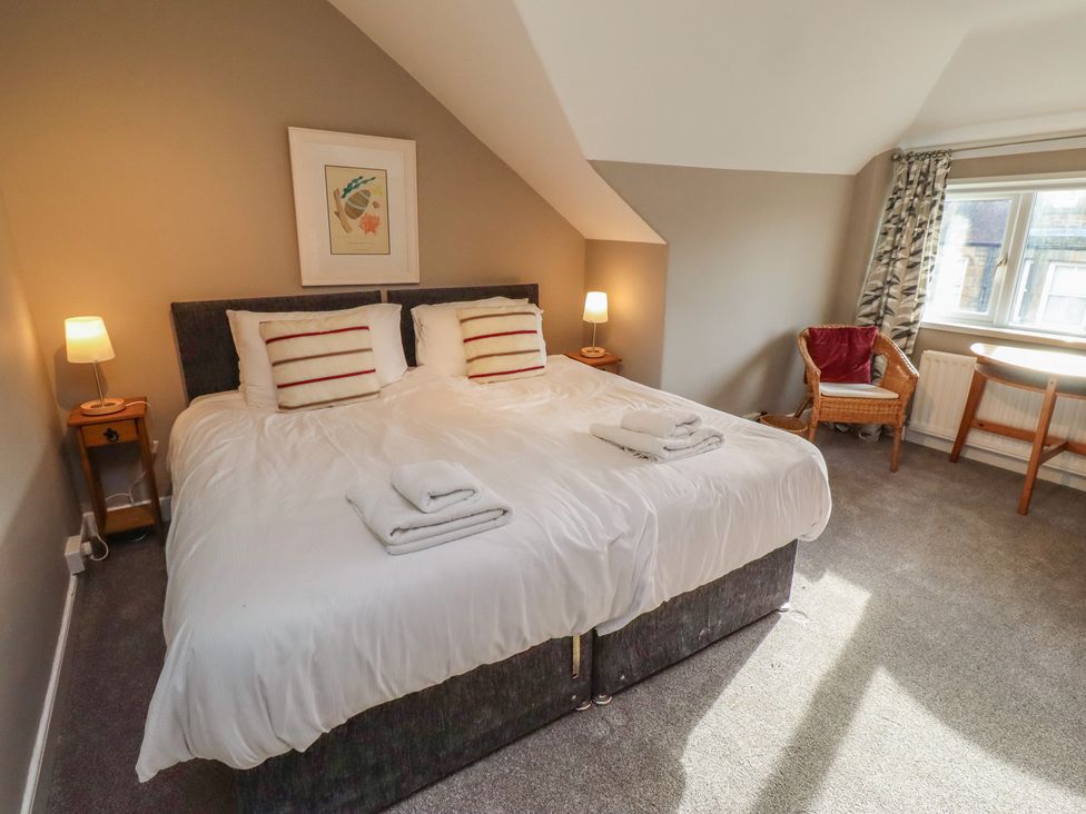 A bedroom with a bed, nightstand, lamp, chair, and window at Rose House in Alnmouth