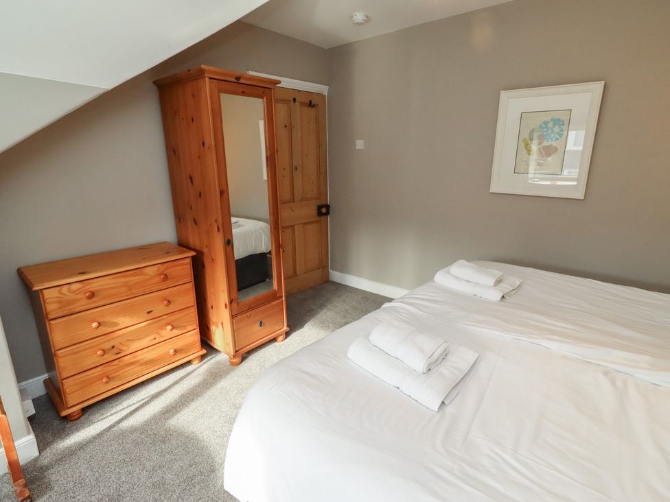 A bedroom with a bed, wardrobe and chest of drawers at Rose House in Alnmouth