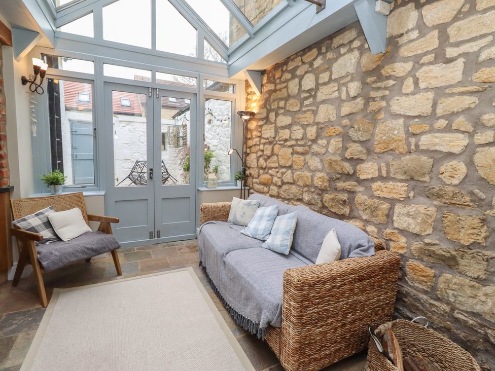 A conservatory with sofa and armchair at Rose House in Alnmouth