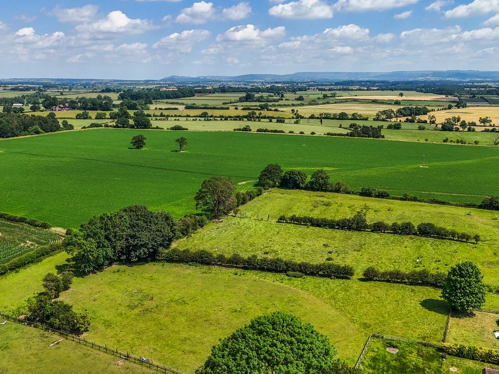 An aerial view of green fields and trees at The Stables in Thirsk