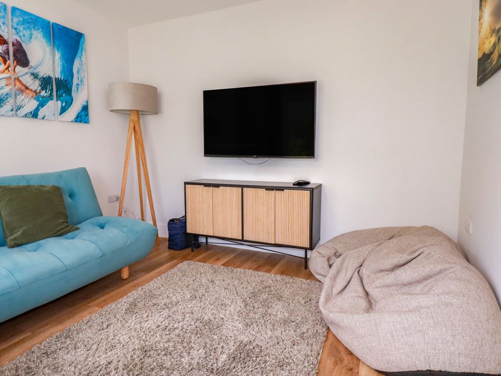 A living room with a sofa and television at Lavender House in Crantock