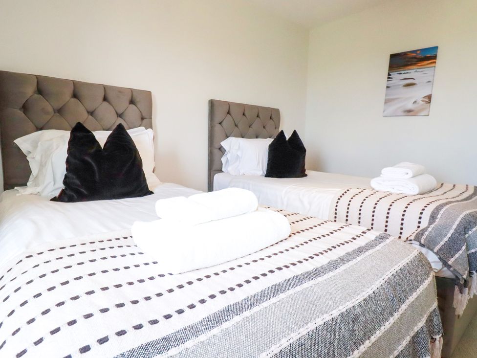 A bedroom with two beds and towels at Lavender House in Crantock