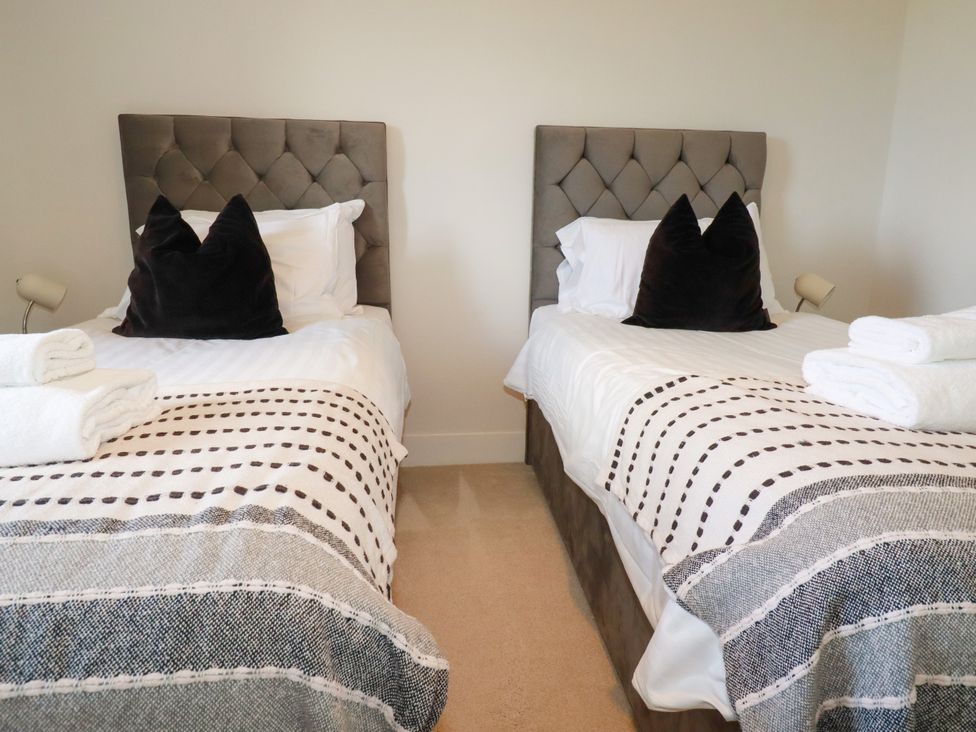A bedroom with twin beds and towels at Lavender House in Crantock