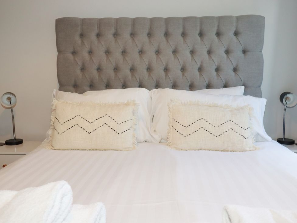 A bed with a tufted headboard and decorative pillows at Lavender House in Crantock