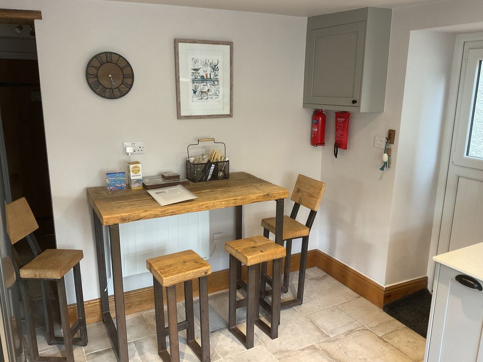 A kitchen with a wooden table and stools at Woodbine Cottage, Mylor Bridge, Nr Falmouth