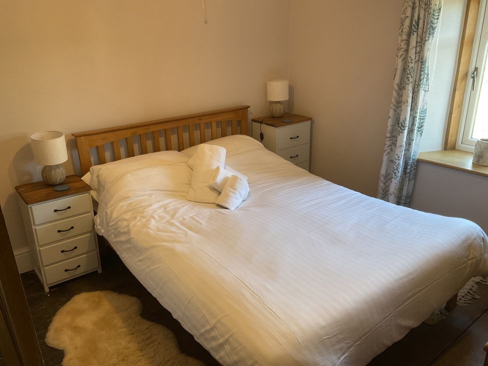 A bedroom with a bed and two bedside tables at Woodbine Cottage, Mylor Bridge, Nr Falmouth