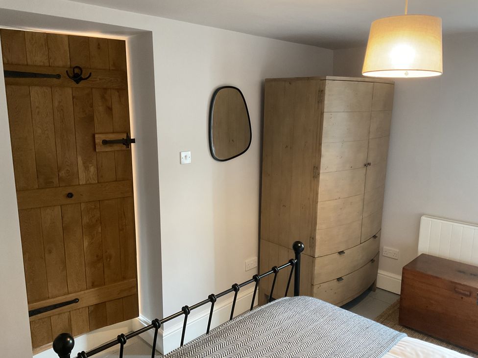 A bedroom with a bed, wardrobe, and door at Woodbine Cottage, Mylor Bridge, Nr Falmouth