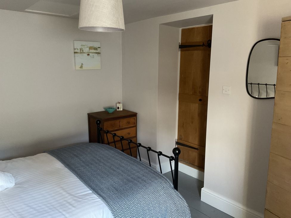 A bedroom with a bed and dresser at Woodbine Cottage, Mylor Bridge, Nr Falmouth