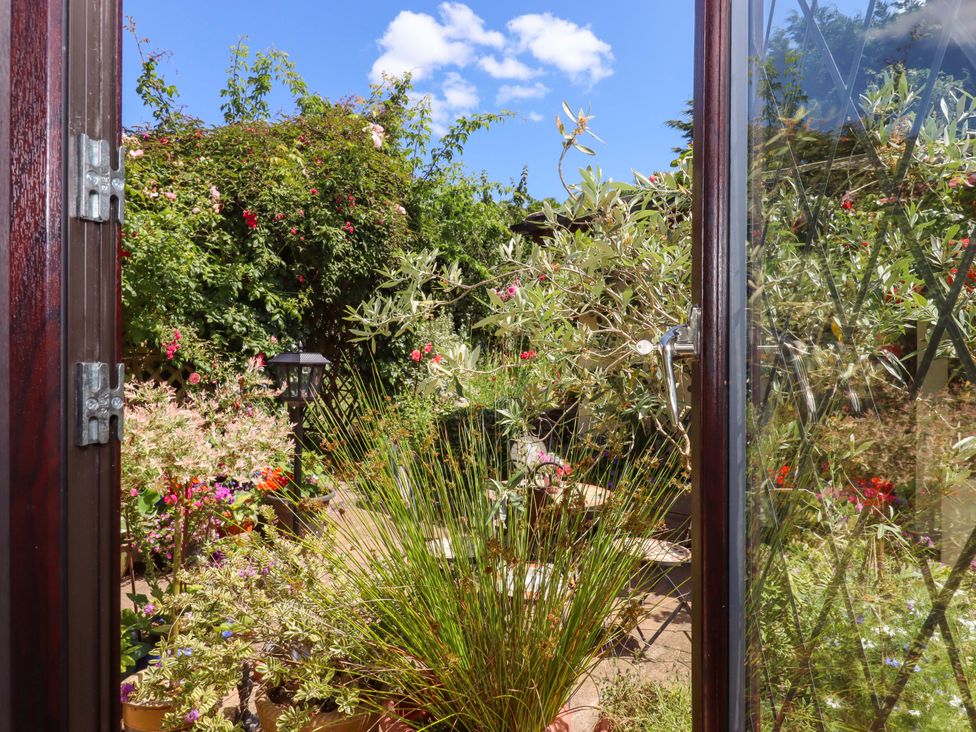 A view of a garden from an open door at Turnpike Lodge in Brixham