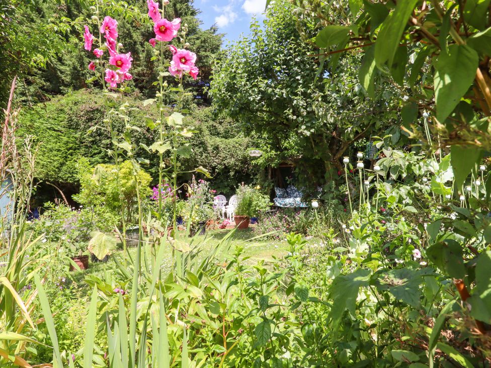 A garden with flowers and chairs at Turnpike Lodge in Brixham