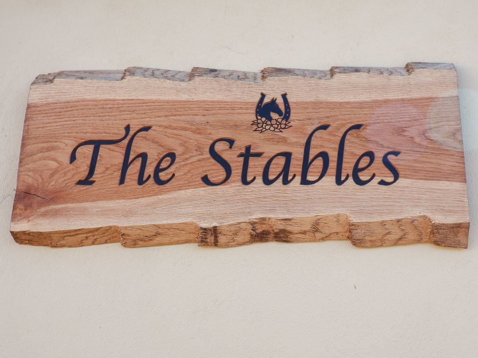 A wooden sign that reads The Stables at The Stables at Hall Barn in Wattisfield near Walsham-Le-Willows