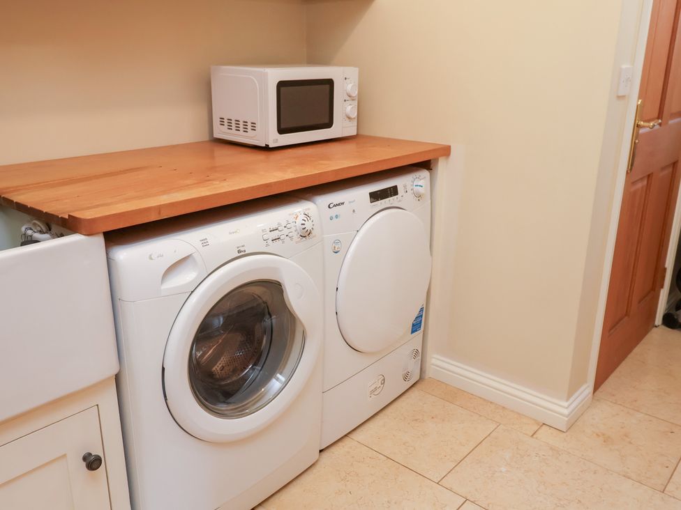 A washing machine and tumble dryer with a microwave on a countertop at The Stables at Hall Barn Wattisfield near Walsham-Le-Willows