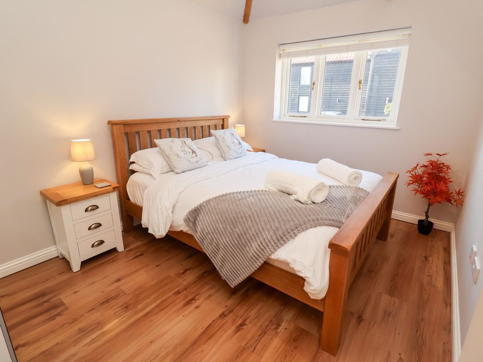 A bedroom with a bed and bedside table at The Stables at Hall Barn Wattisfield near Walsham-Le-Willows