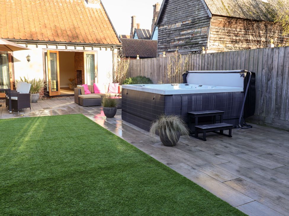 A garden with a hot tub and seating area at The Stables at Hall Barn Wattisfield near Walsham-Le-Willows