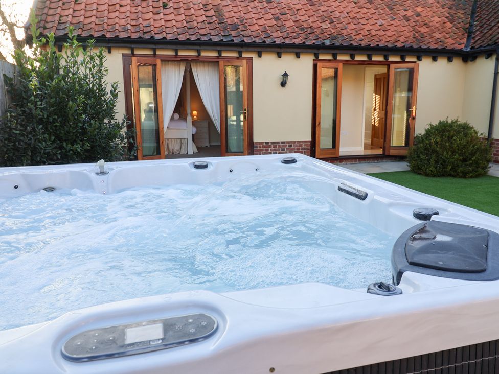 A hot tub with spray and open doors at The Stables at Hall Barn Wattisfield near Walsham-Le-Willows