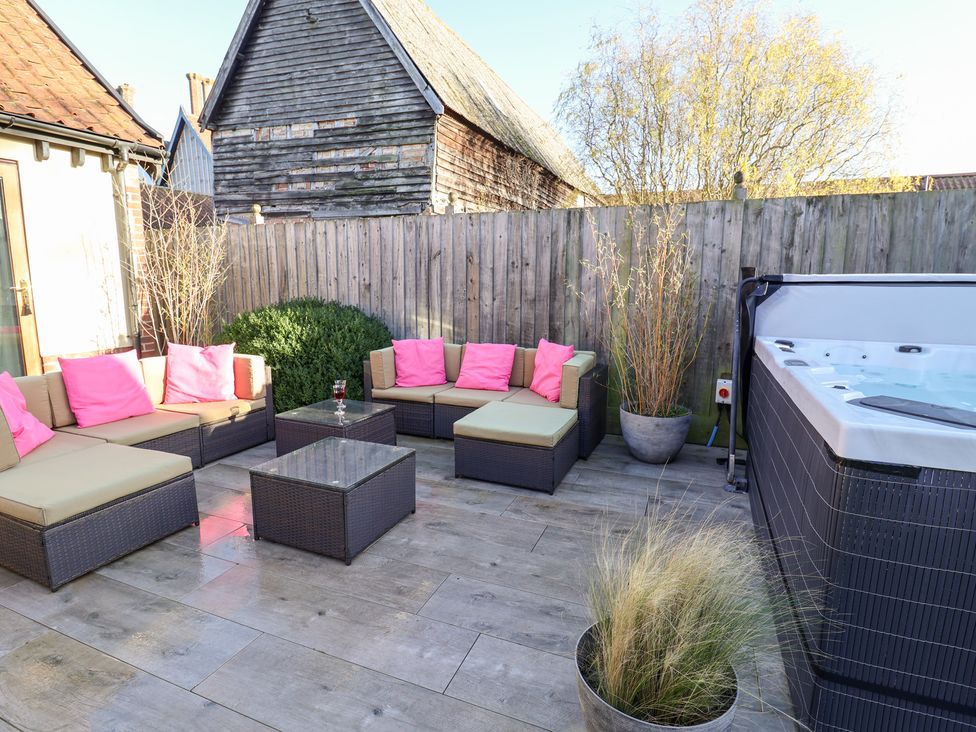 An outdoor patio with a hot tub and seating area at The Stables at Hall Barn in Wattisfield near Walsham-Le-Willows