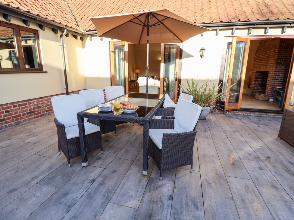 An outdoor seating area with a table and chairs at The Stables at Hall Barn, Wattisfield near Walsham-Le-Willows