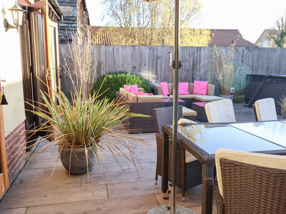 An outdoor area with a table, chairs, and a sofa at The Stables at Hall Barn Wattisfield near Walsham-Le-Willows