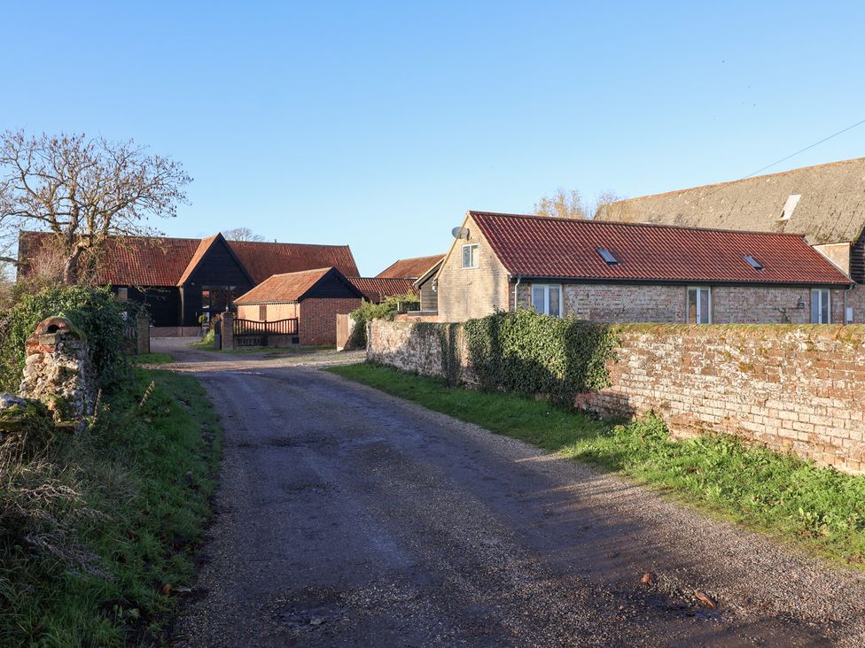 An outdoor view of barns and a house at The Stables at Hall Barn Wattisfield near Walsham-Le-Willows