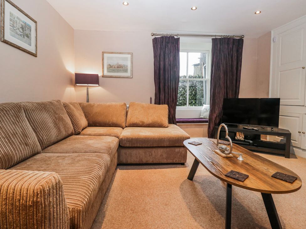 A living room with a sofa and television at The Old Book Shop in Cartmel