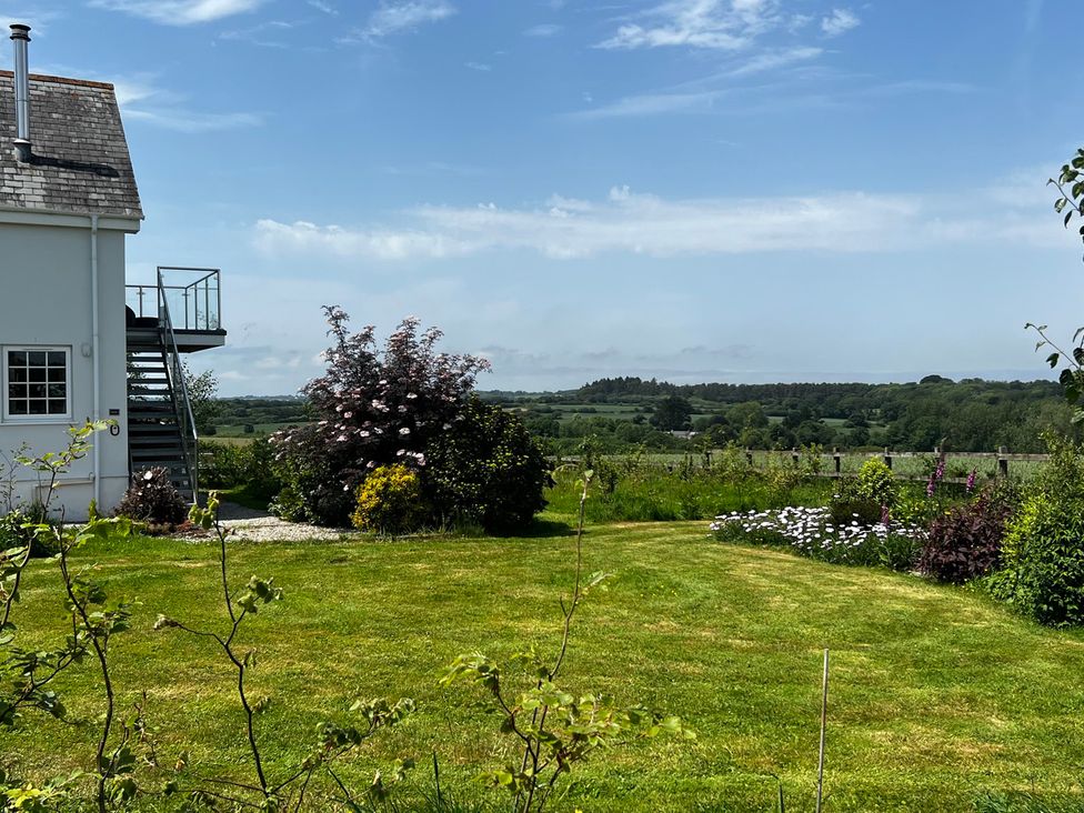 A garden with a house, stairs, and flowers at Spires in Playing Place near Carnon Downs
