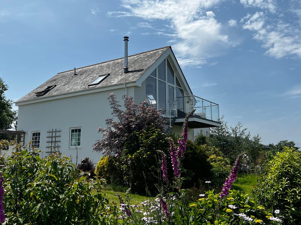 A house with a balcony surrounded by a garden at Spires Playing Place near Carnon Downs
