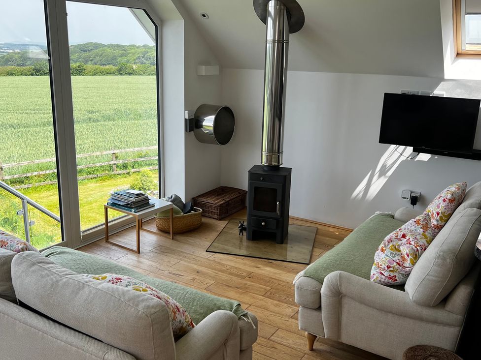 A living room with a wood stove and television at Spires in Playing Place near Carnon Downs