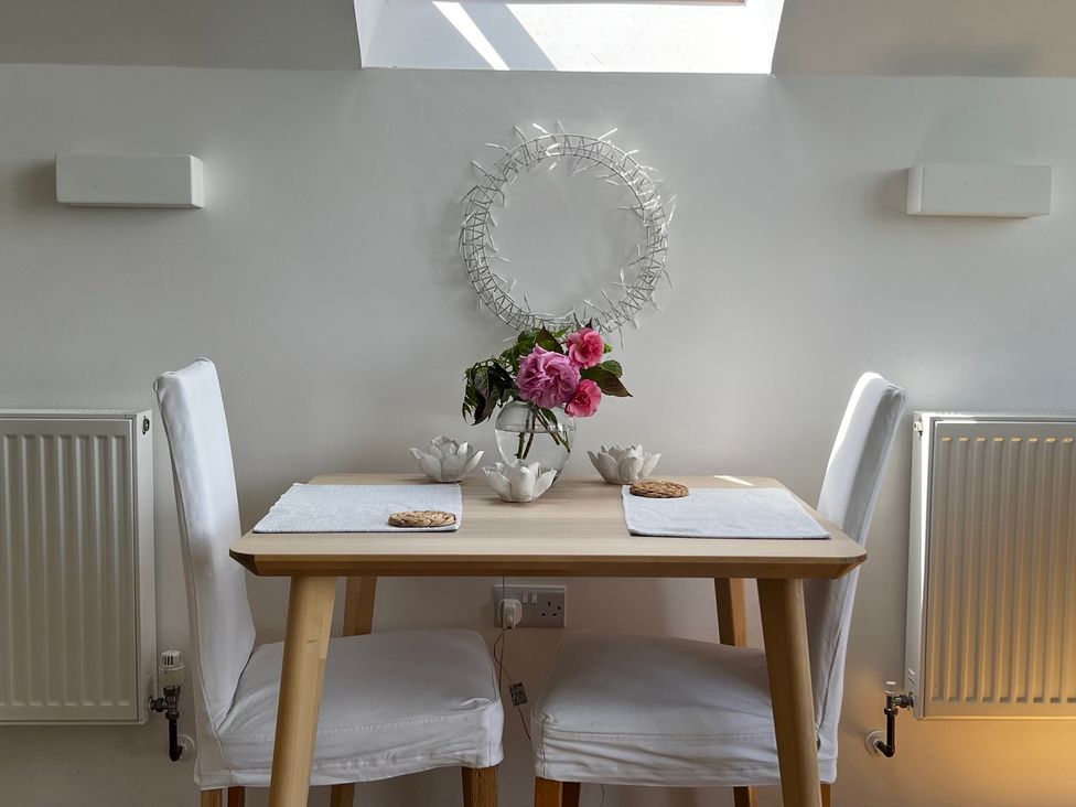 A dining room with a table and flowers at Spires Playing Place near Carnon Downs