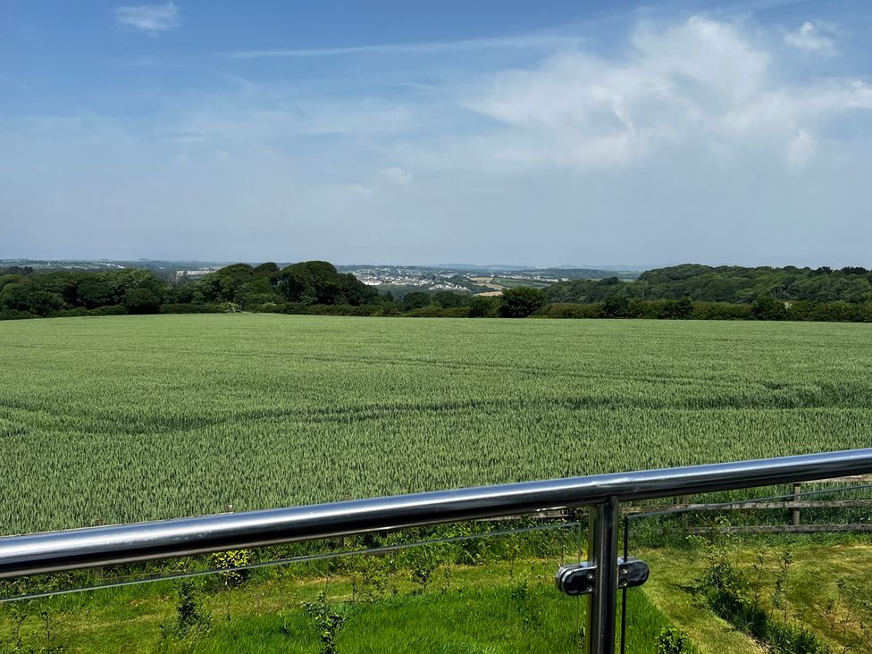 A view of a field with trees and hills from a railing at Spires Playing Place near Carnon Downs