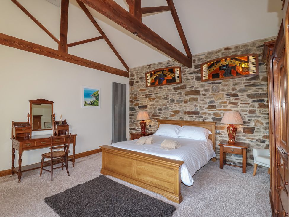 A bedroom with a bed and a wooden wardrobe at Birchenhayes in St Dominick
