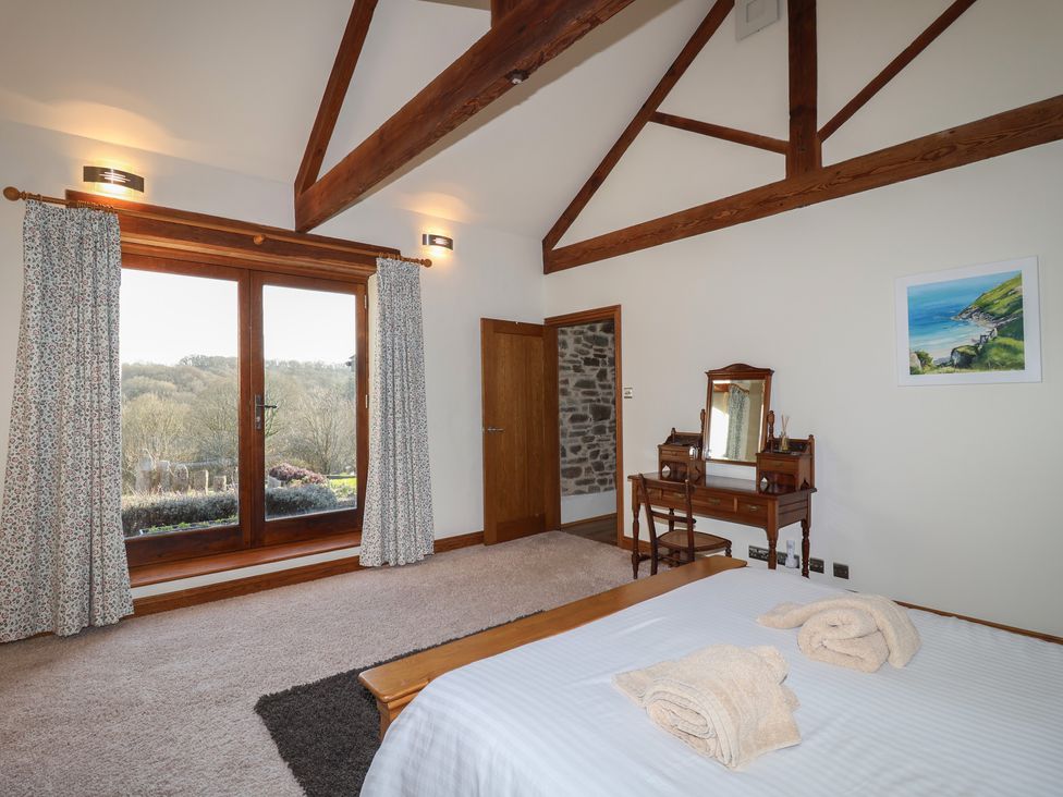 A bedroom with a bed and a dressing table at Birchenhayes St Dominick