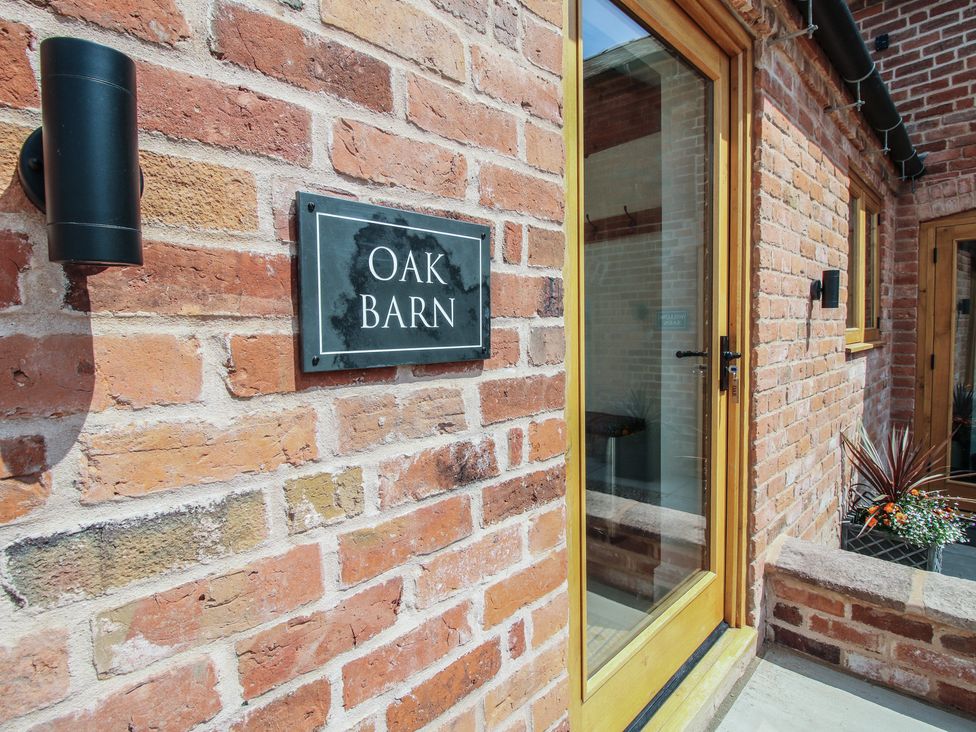 An entrance with a sign and light fixture at Oak Barn