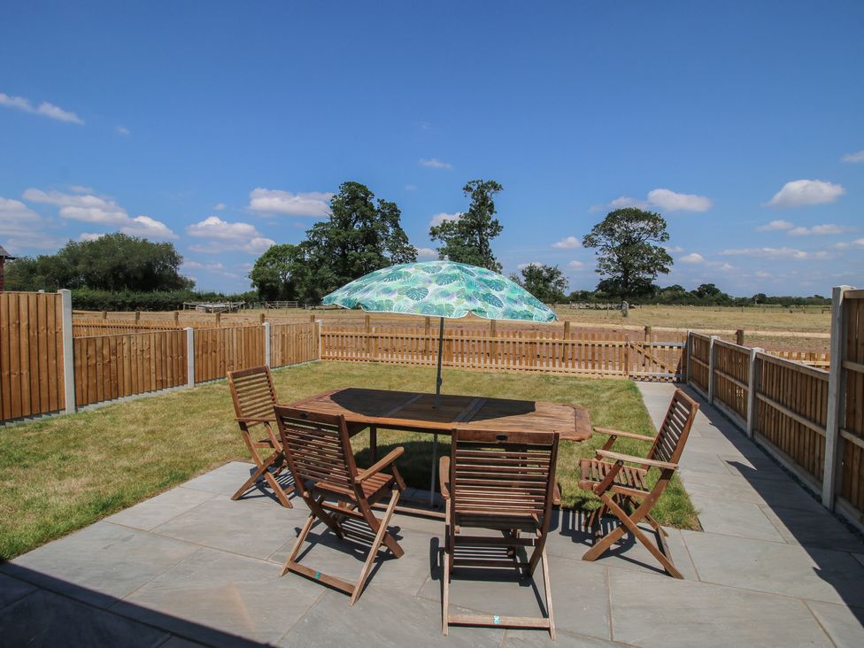 A garden with table and chairs under an umbrella at Oak Barn