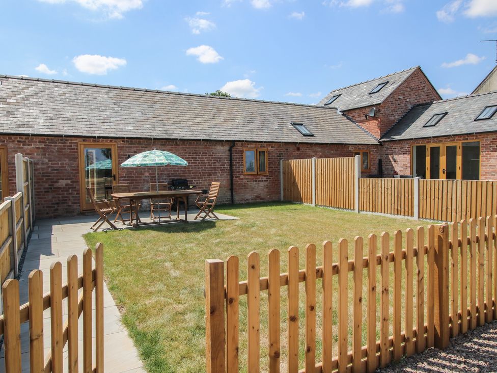 A garden with a table and chairs under an umbrella at Oak Barn in 