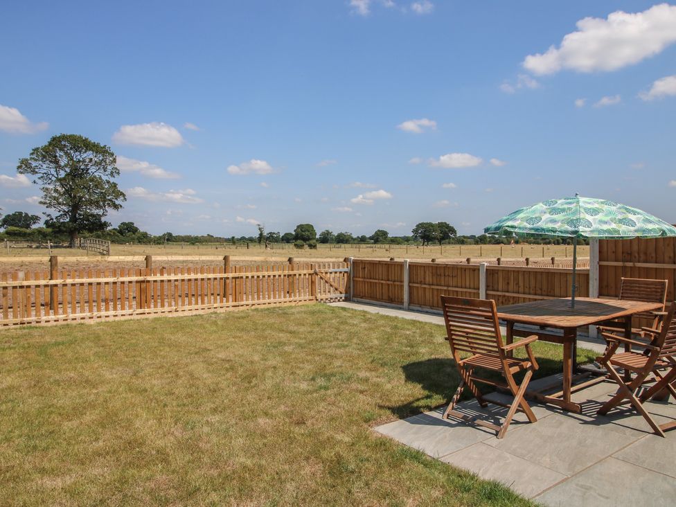 A garden with a table and chairs under an umbrella at Oak Barn