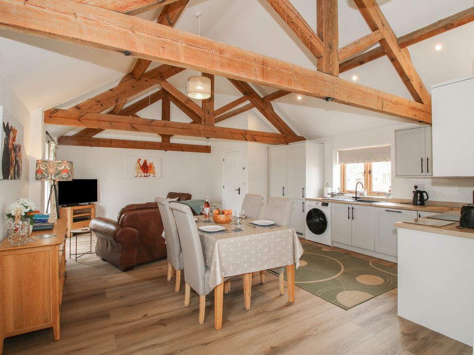 A living room with a dining table and kitchen area at Oak Barn near Wem