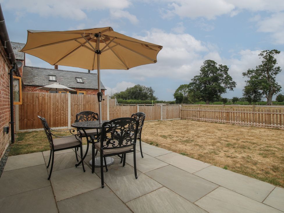 A garden with a table and chairs under an umbrella at Oak Barn Northwood near Wem