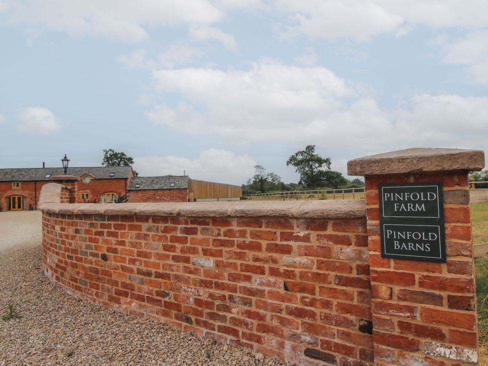 An outdoor area with a brick wall and sign at Pinfold Farm near Wem