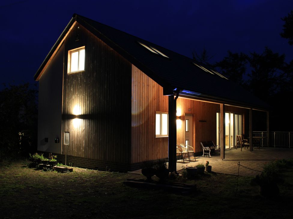 A house with lights on and chairs on the porch at Narracott Down South Molton