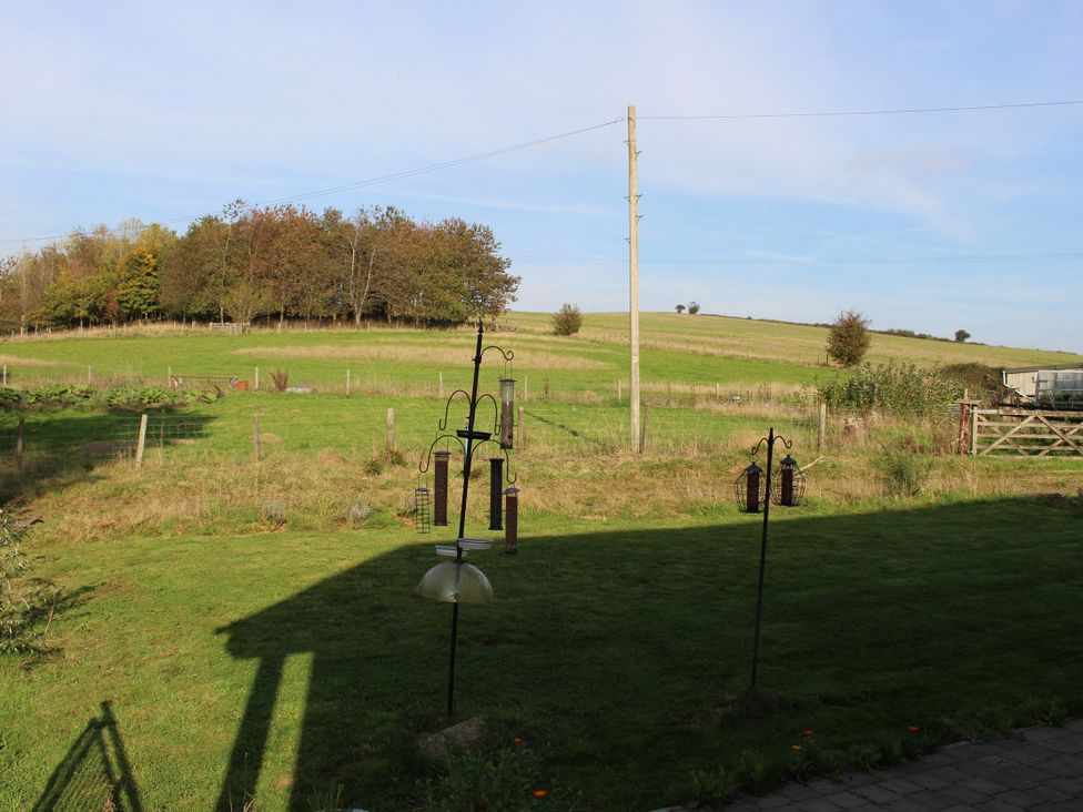 A garden with bird feeders and a view of fields at Narracott Down in South Molton