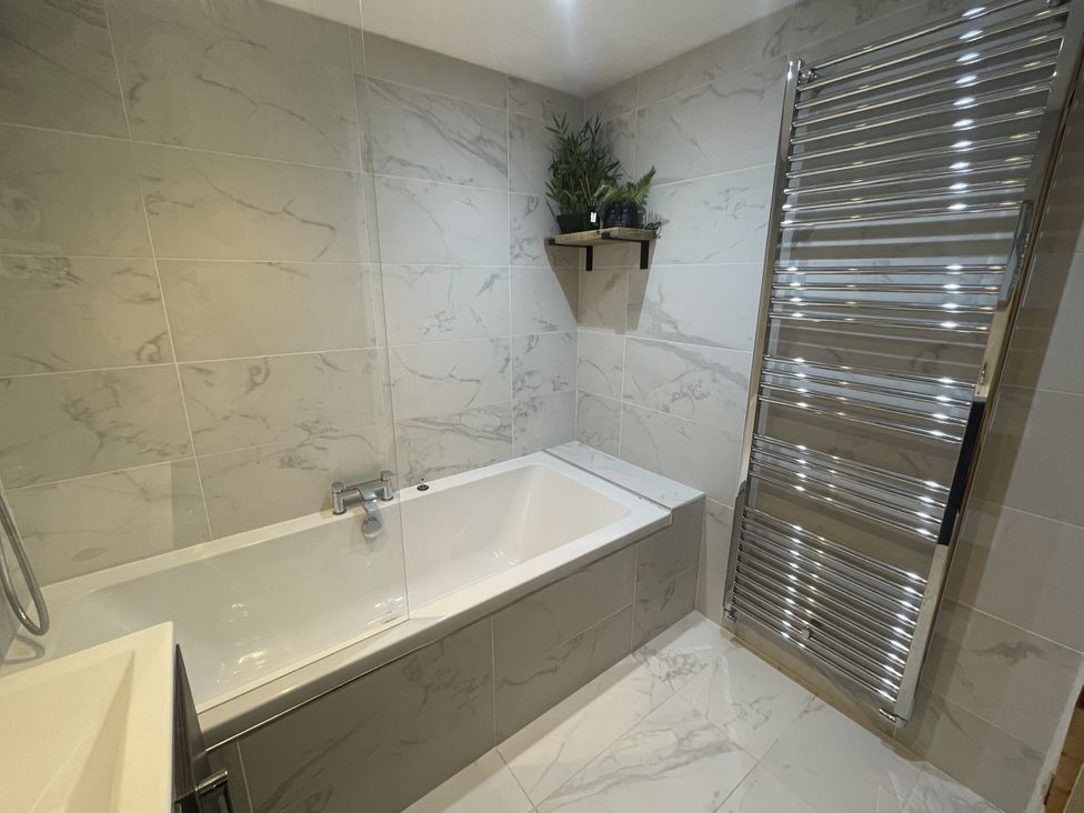 A bathroom with a bathtub and towel radiator at Old Chapel House in Llanfairfechan