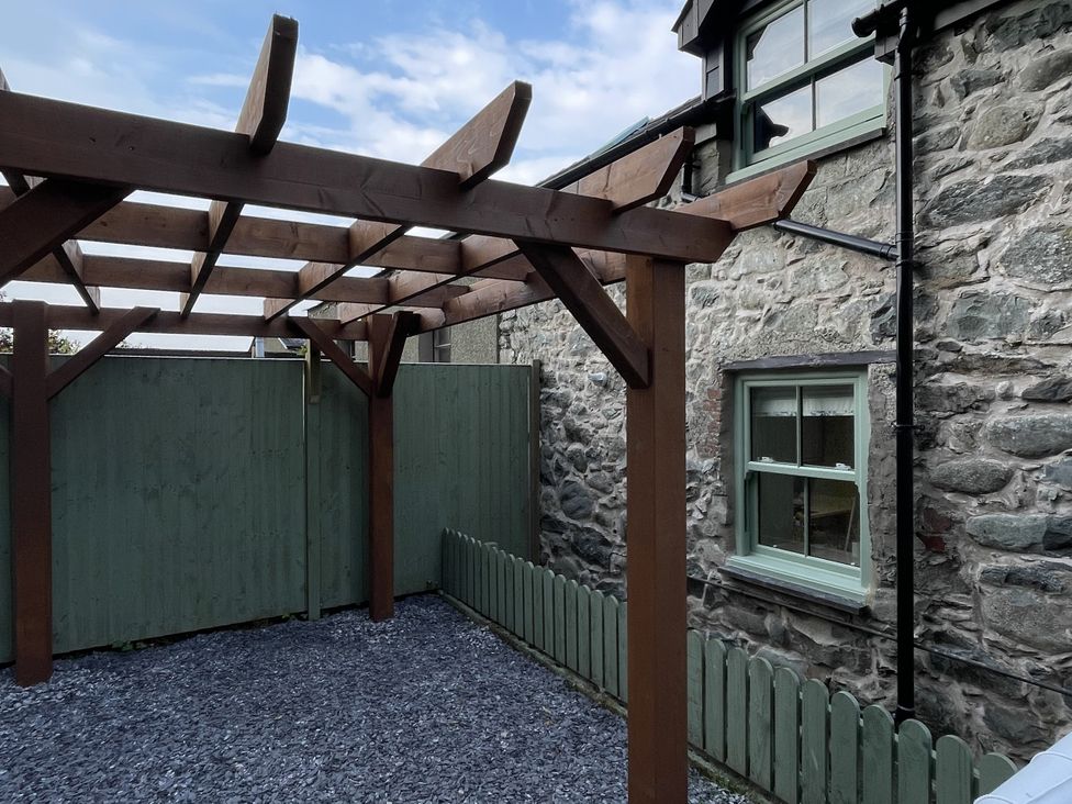 An outdoor area with a pergola and stone walls at Old Chapel House Llanfairfechan