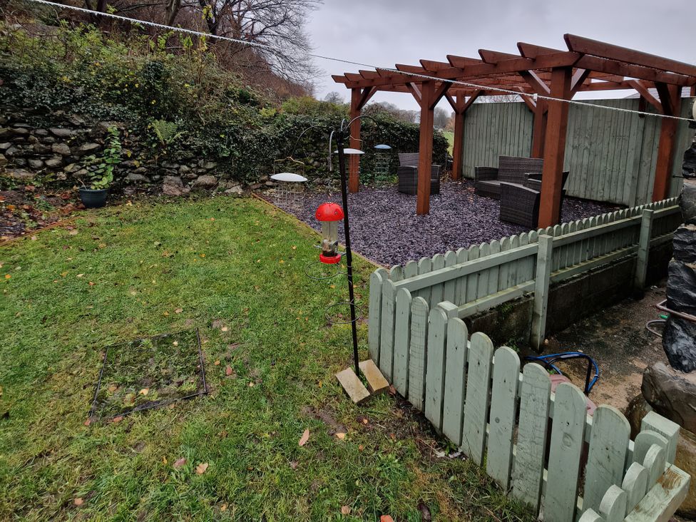 A garden with a bird feeder and patio furniture at Old Chapel House Abergwyngregyn near Llanfairfechan