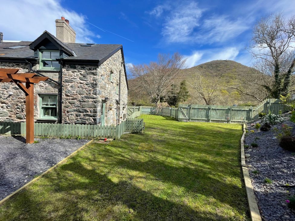 A garden with a stone house and mountain in the background at Old Chapel House Abergwyngregyn near Llanfairfechan