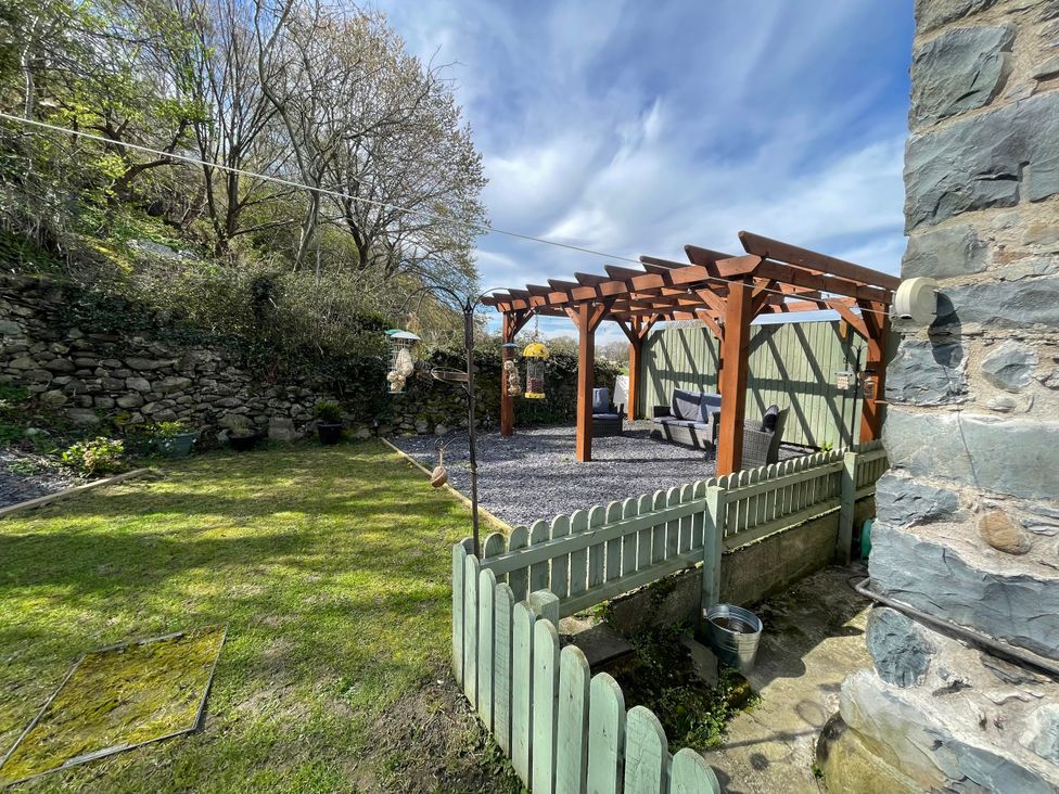 A garden with a pergola and gravel area at Old Chapel House Abergwyngregyn near Llanfairfechan