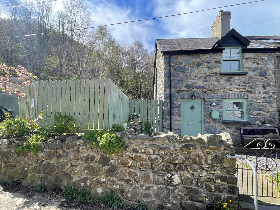 A stone cottage with a green door and wooden fence at Old Chapel House in Abergwyngregyn near Llanfairfechan