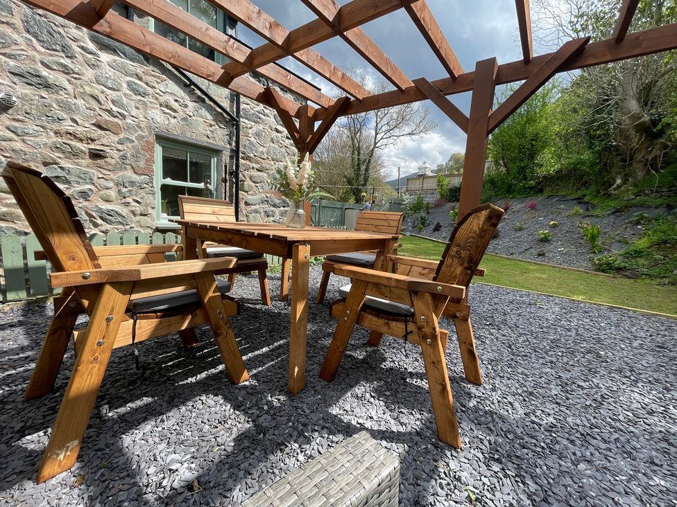 A garden with wooden furniture under a pergola at Old Chapel House Abergwyngregyn near Llanfairfechan