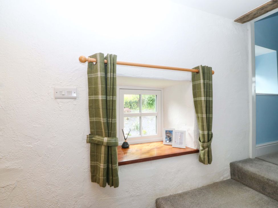 A window with curtains and decorative items on the sill at Old Chapel House Abergwyngregyn near Llanfairfechan