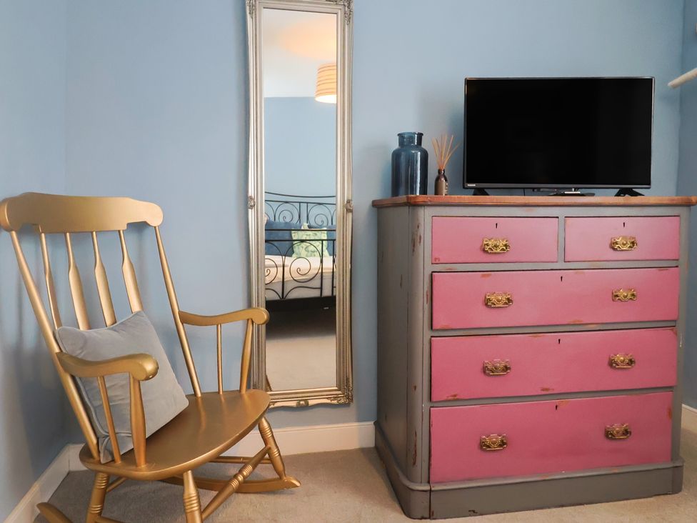 A bedroom with a rocking chair and a dresser at Riverdance Cottage in Lyme Regis
